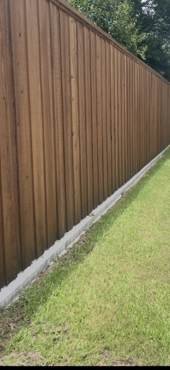 8 foot cedar board on board fence with double trim, stain, and a concrete footer